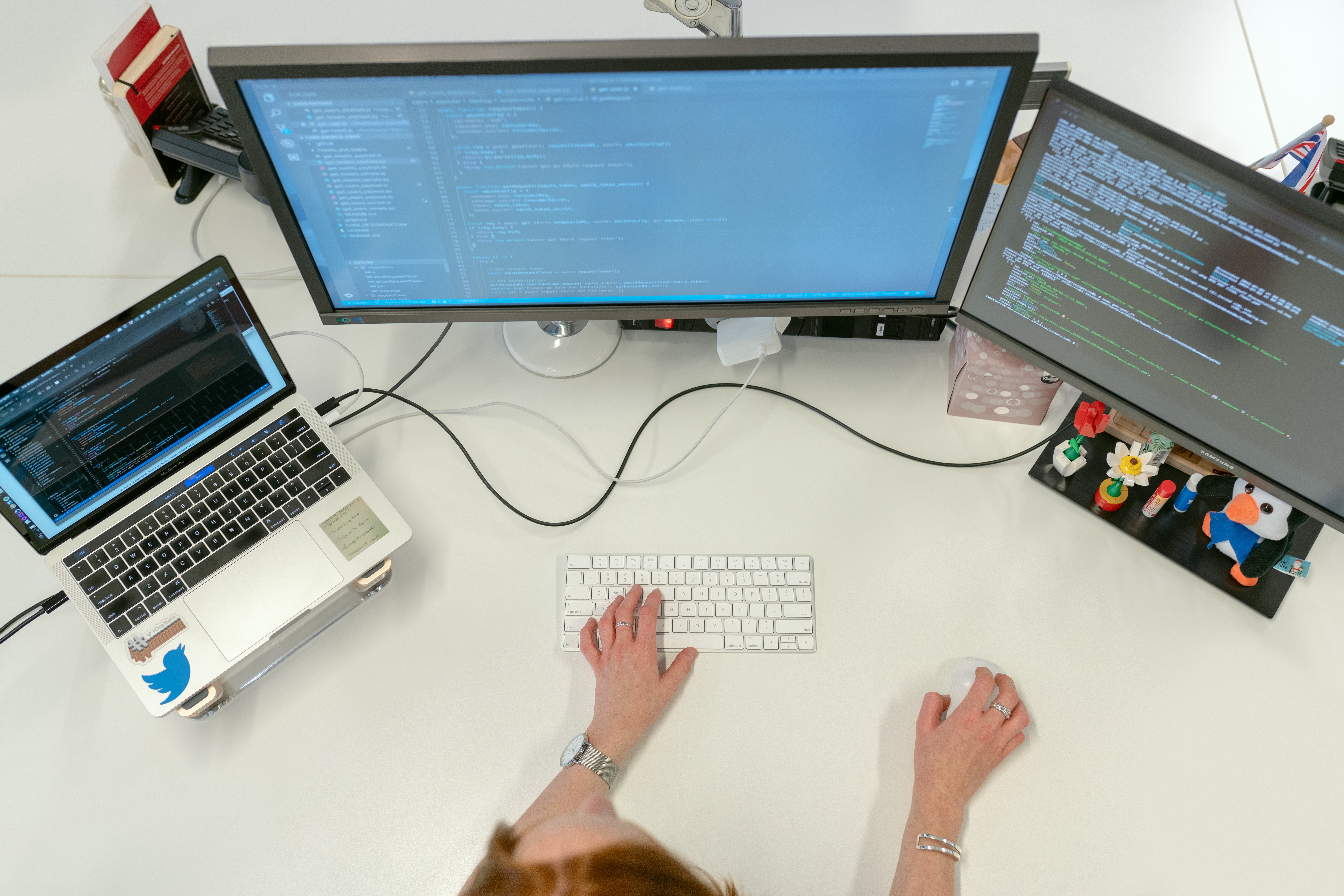 A female engineer typing code on a multi monitor setup