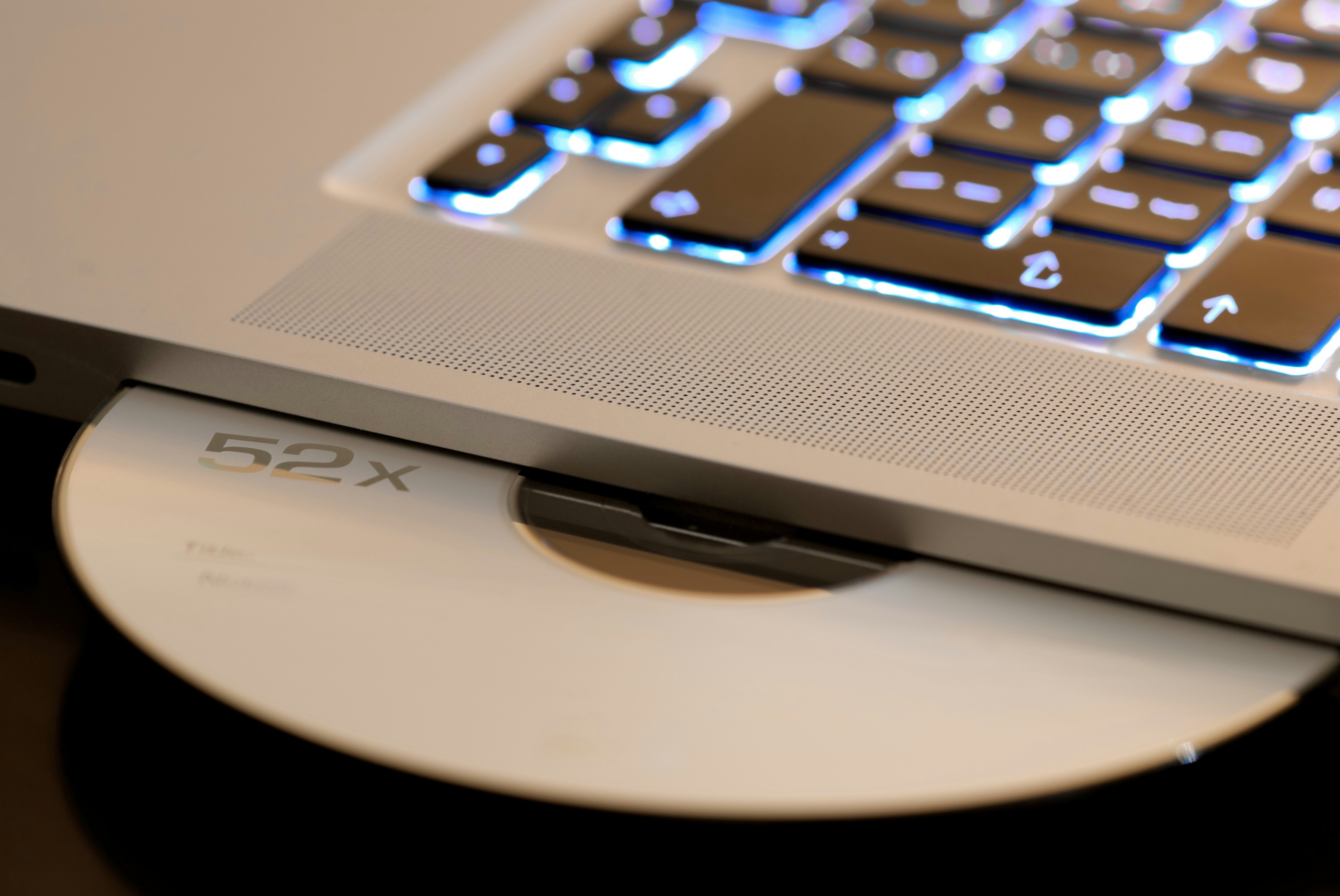 A CD being inserted into the drive of a laptop